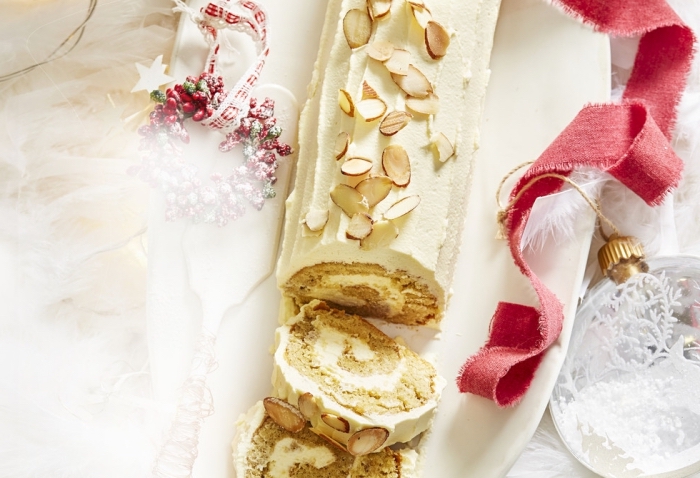 recette de buche de noel classique au chocolat blanc et au gingembre décoré avec des amandes effilées, gâteau roulé au glaçage de chocolat blanc strié 