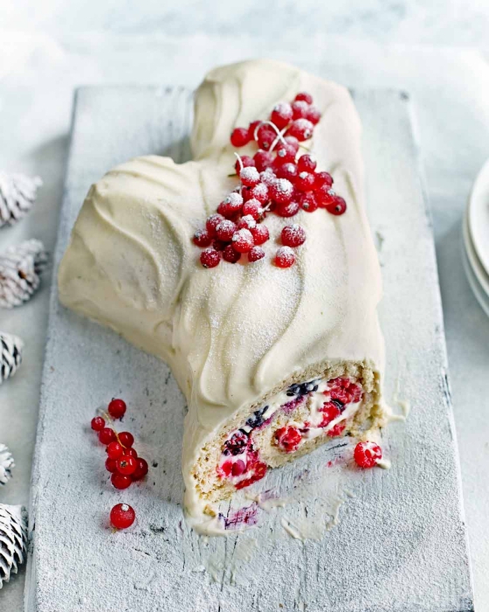 buche glacée maison à la vanille, aux fruits rouges et au glaçage de chocolat blanc, présentée sur une planche bois blanche, déco de table de noël blanche enneigée