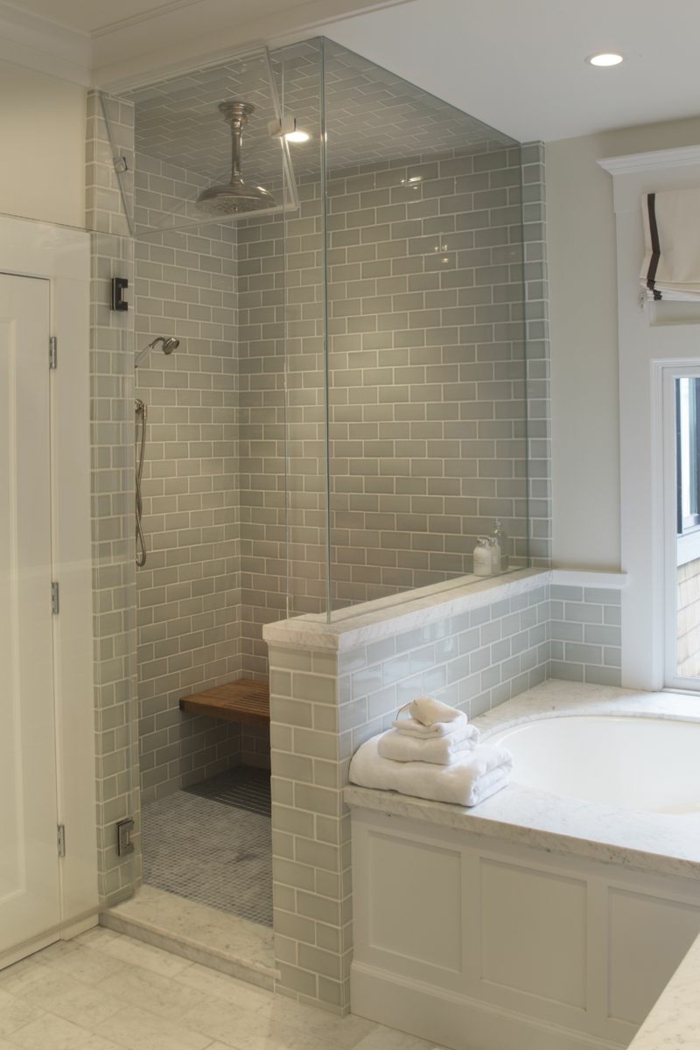 intérieur de salle de bain gris, banquette de salle de bain suspendue en bois, douche montée au plafond, mur carreaux métro et cloison transparente
