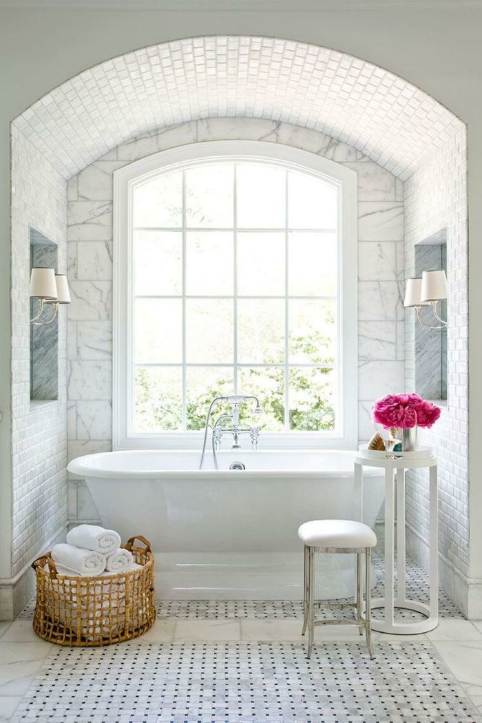 salle de bain blanche, panier tressé, petit tabouret, table ronde haute, bouquet fleurs roses, porte-fenêtre arquée, carrelage vintage