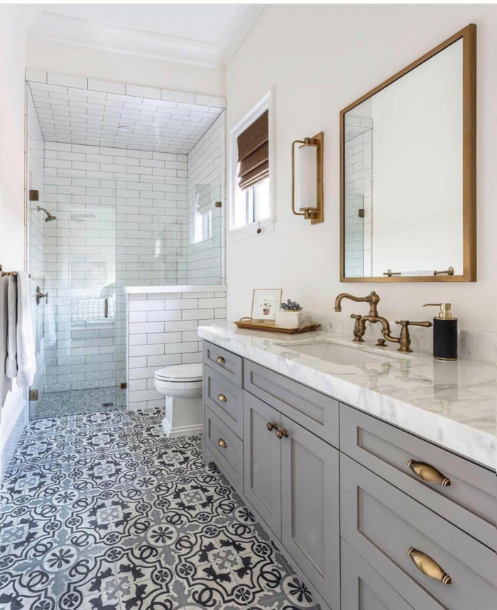 salle de bain en blanc et gris, motifs carreaux de ciment, douche plain pied, cadre de miroir cuivré, robinet cuivré vintage