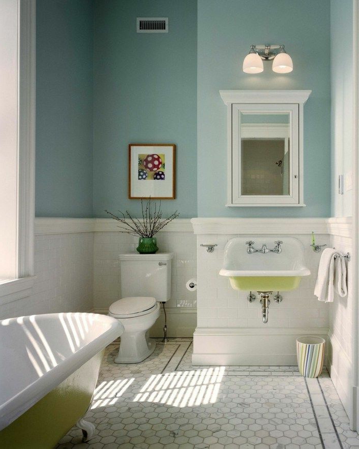mur bleu, tomettes blanches, baignoire blanc et vert, placard avec miroir, lavabo vintage en résine en blanc et vert, cadre peinture