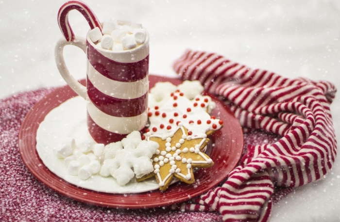 idée chocolat chaud romantique au lait, boisson chaude de Noel servie avec guimauves et sucre d'orge dans mug blanc et rouge