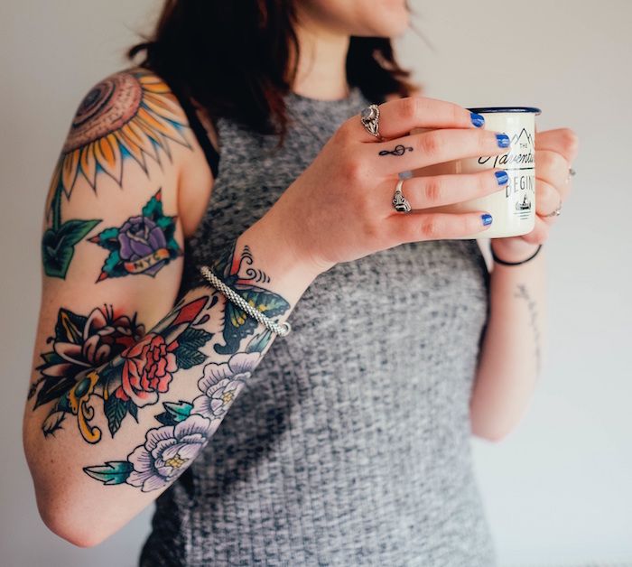 tatouages old school en couleurs sur bras femme avec fleurs roses et tattoo tournesol sur l'épaule