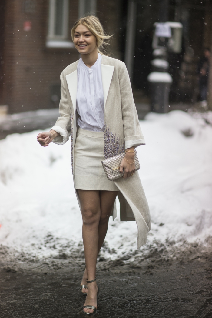 manteau gris clair, jupe moulante courte, sac enveloppe métallique, chemise blanc sandales élégantes