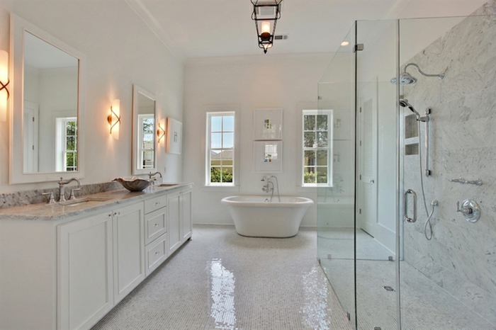 déco de salle de bain blanche, sol en petites tuiles blanches, meuble sous vasque blanc, grands miroirs, cabine de douche et baignoire, appliques cylindriques