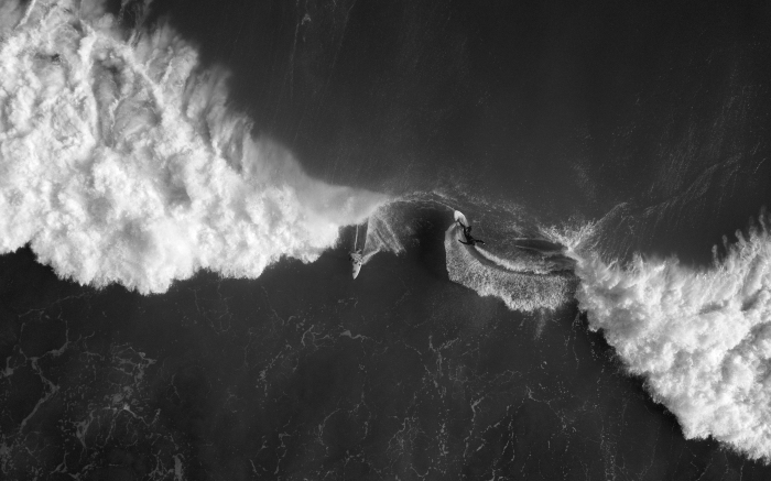 belle photo noir et blanc de surfeur et de bateau en plein océan dans du surfeur