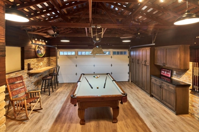 aménagement salle de jeux dans un garage, déco de style rustique avec murs en pierre et plafond de bois foncé