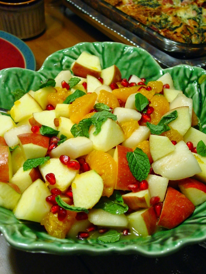 jolie salade de fruits d'hiver, pommes, poires, graines grenade, menthe, mandarines tranchées, dessert apétissant