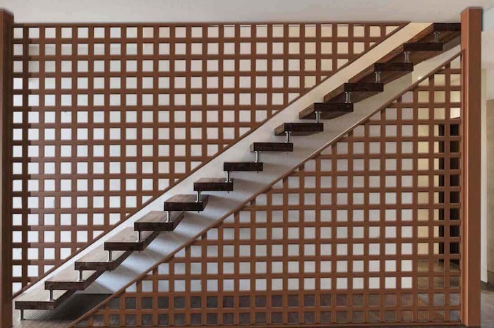 grande claustra en bois avec ouvertures carrées utilisée comme séparateur et paroi d'escalier dintérieur