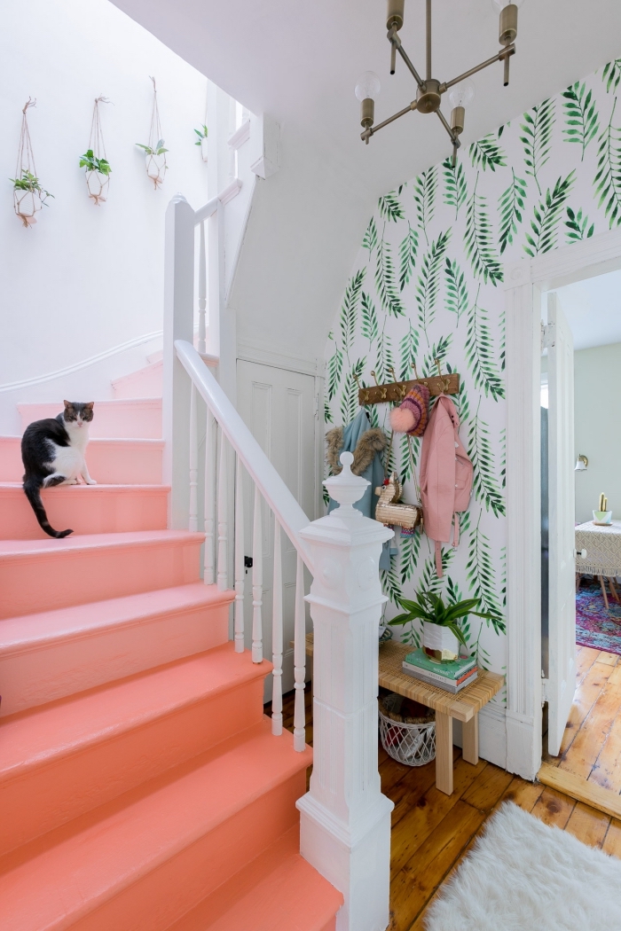 idée originale pour relooker un escalier en bois, déco cage d'escalier d'ambiance estivale et tropicale avec marches peintes en rose pastel et un papier peint à motifs végétaux 
