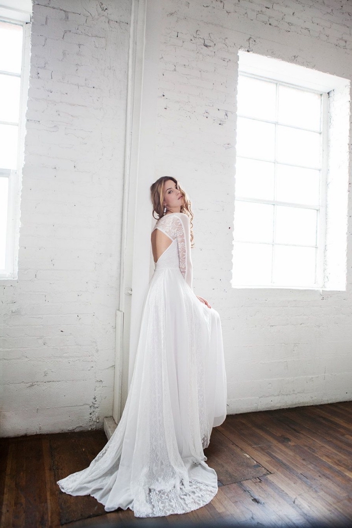 dos-nu-en-losange-robe-de-mariée-originale-avec-jupe-fluide-brodée-dos-ouvert-manches-longues-transparentes-coiffure-de-mariée-cheveux-bouclés vision romantique pour femme mariage, robe de mariée manche dentelle à dos nu en losange et applications dentelle