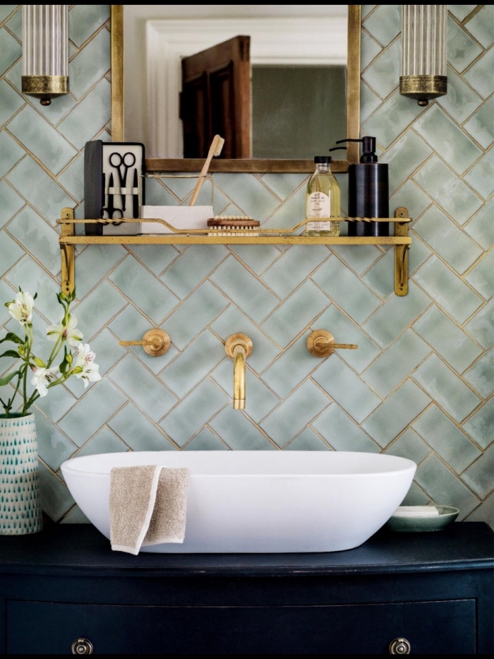 crédence élégante en mise en valeur par le robinet mural et l'étagère dorée, posée en dessus d'un meuble sous vasque bleu marine