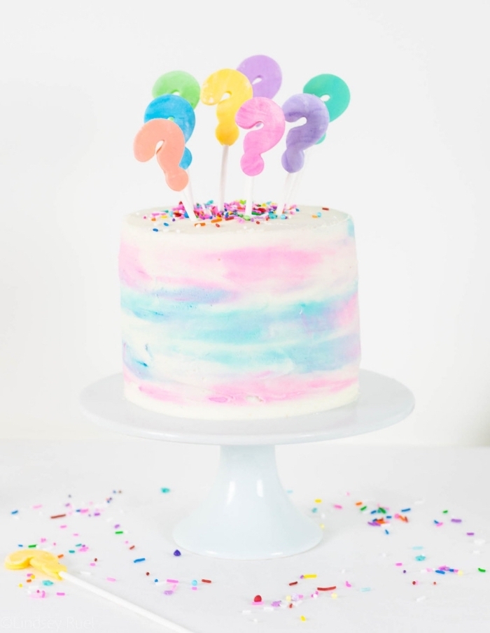 délicieux pinata cake pour un baby shower, gâteau au glaçage aquarelle rempli de bonbons roses, décoré de cake toppers points d'exclamation