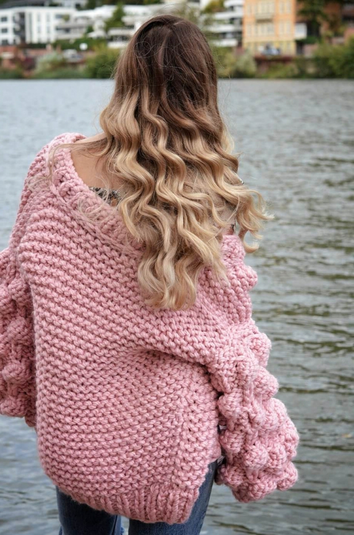 pull oversize femme rose, manches originales, gros pull en maille porté par une femme blonde au bord de la rivière