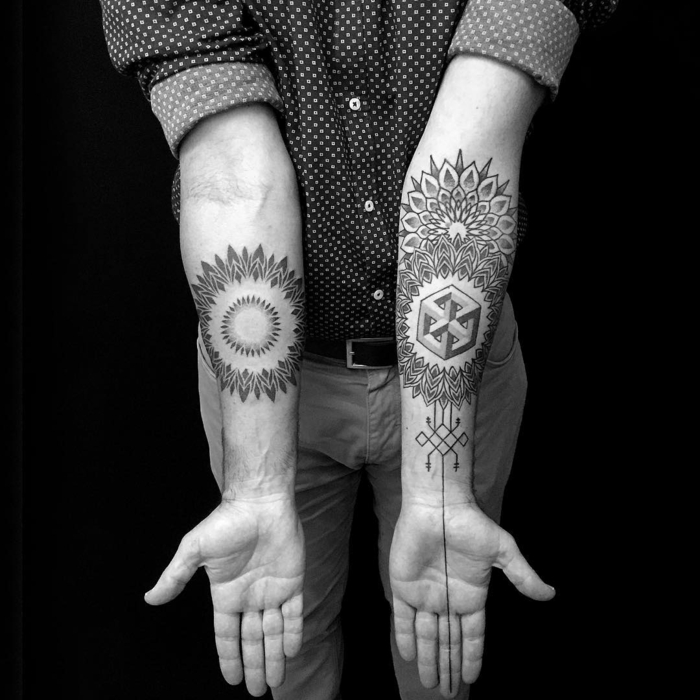 Dessin stylisé de mandala et illusion optique de Esher, tatouage géométrique sur l'avant bras, idée tatouage homme style graphique, homme qui porte chemise à pois, pantalon beige et ceinture 