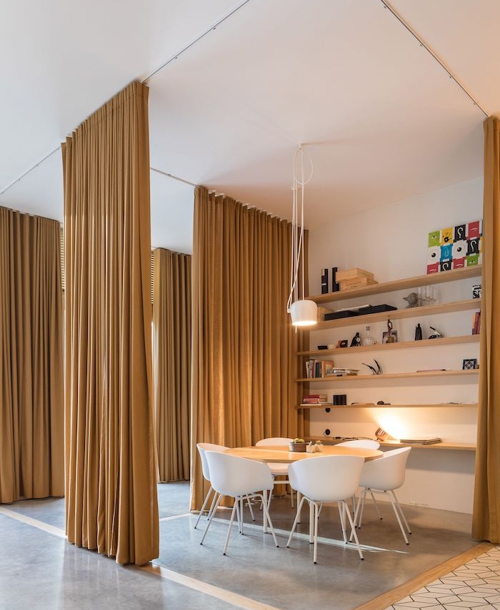 rideau séparateur sur rail couleur jaune moutarde pour isoler une salle à manger scandinave avec chaises blanches, étagère murale bois