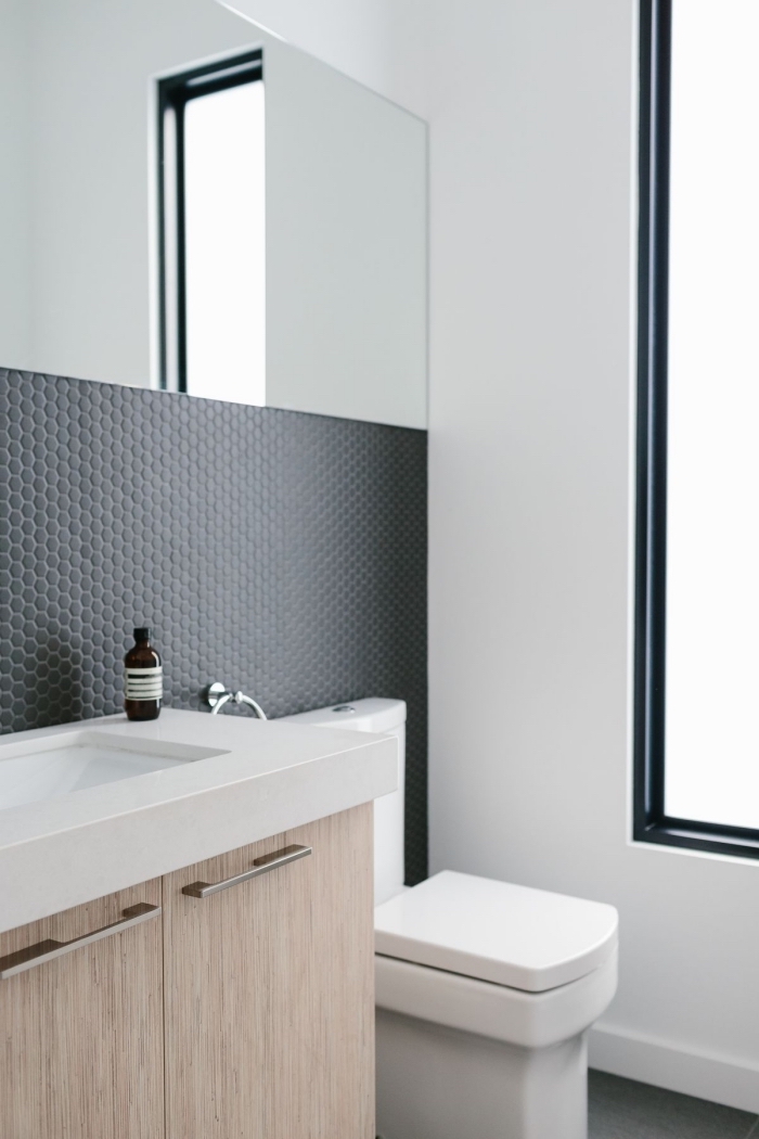une crédence adhésive imitation mosaique hexagonal à finition noire mate qui apporte une touche d'élégance à la salle de bains blanche