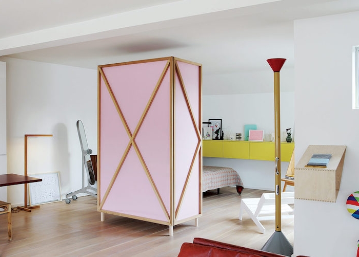 paravent de separation couleur rose et bois pour décorer une chambre à coucher design avec lit, rangement mural couleur jaune, parquet clair