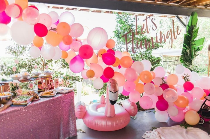 flamingue rose, déco de ballons roses, oranges et blancs, table avec repas de fête, anniversaire d'enfant