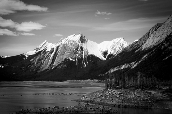 paysage noir et blanc des méandres d'une rivière au pied des pics enneigés de la montagne sous un ciel gris