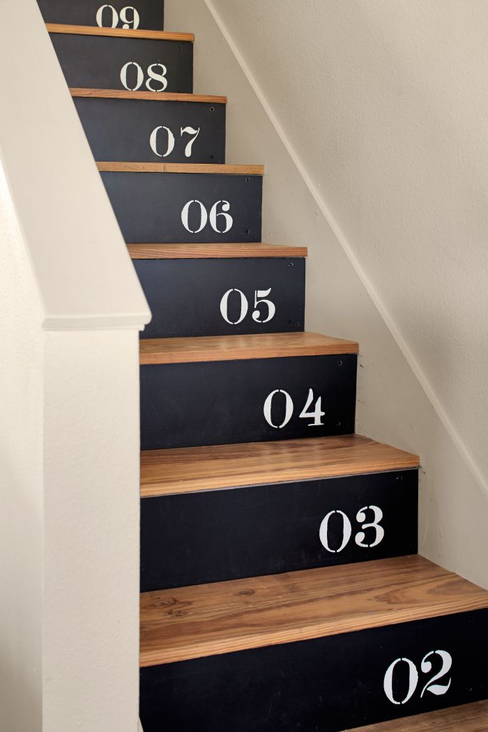 escalier en bois aux contremarches peintes en noir avec des chiffres réalisés au pochoir en joli contraste avec le bois des marches