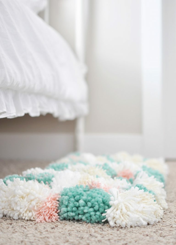 un tapis pompon épais disposé sous le lit, tapis aux couleurs blanc et turquoise, lit shabby