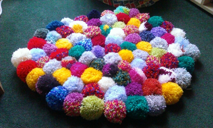tapis laine bariolé, plusieurs pompons colorés assemblés ensemble en tapis rond moelleux