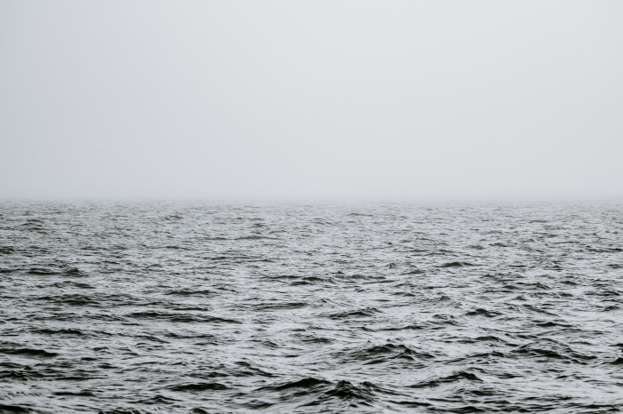 une photo noir et blanc de mer et l'horizon caché par le brouillard, photographie de paysage marin monochrome