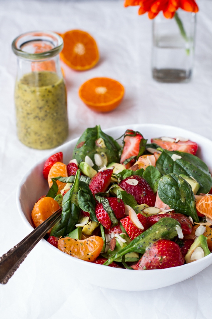 salade d'hiver avec fraises décongelées, feuilles d'épinards, mandarines en tranches, graines et purée de kiwi comme garniture