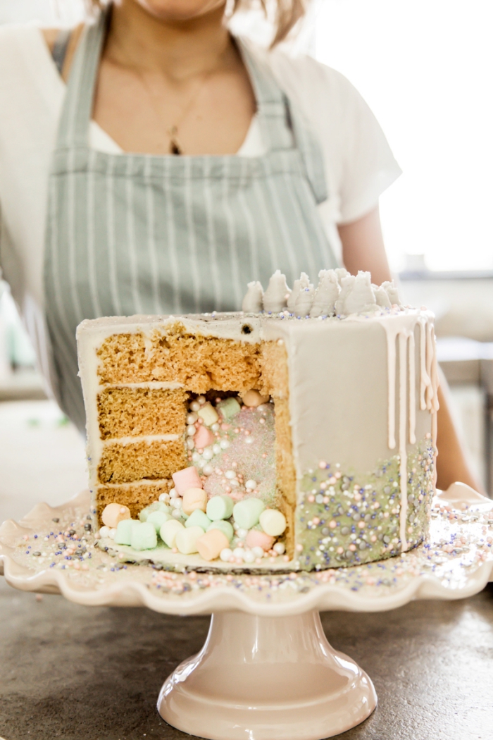 gâteau surprise à couches de génoise vanille, au glaçage coulant rempli d'un mix de poudre comestible, perles en sucre et guimauves