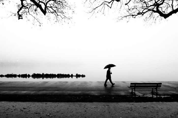photographie noir et blanc promenade au bord de l'eau, photo monochrome montrant un homme tenant un parapluie 