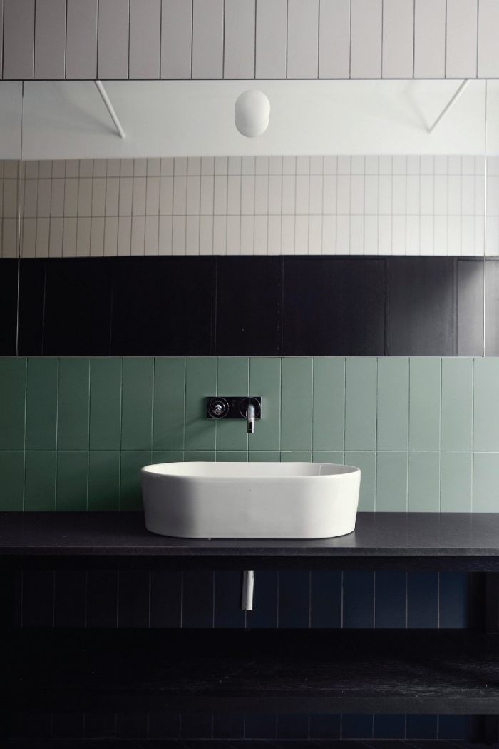 une crédence de salle de bains originale composée de deux rangée de carreaux verts posés horizontalement, une salle de bains où on mélange trois revêtements muraux