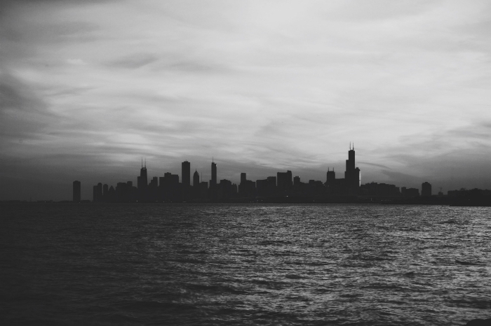 image noir et blanc de silhouette d'une ville se dessinant à l'horizon derrière les eaux calmes de la mer