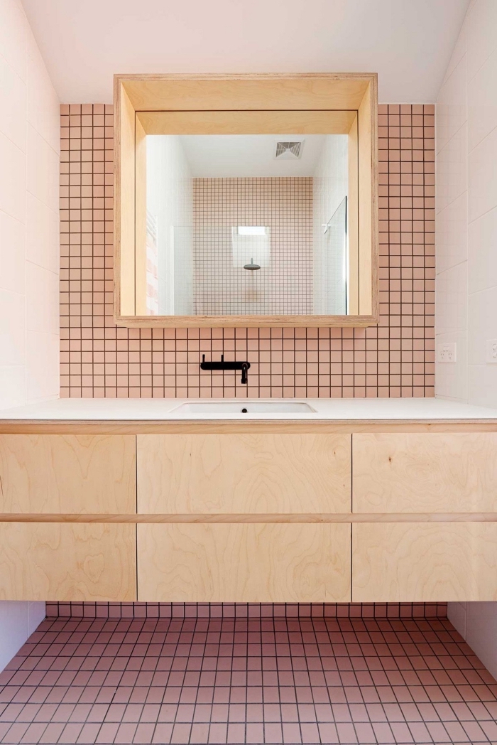 revêtement de sol et mur en carrelage rose pour une salle de bains d'aspect vintage, meuble sous vasque à finition bois naturel associé à un miroir étagère fonctionnelle