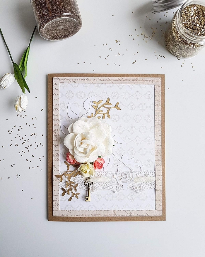 diy carte anniversaire en papier beige avec lettres imitation page de livre, carte fait main avec fleur blanche et figurine clé métal