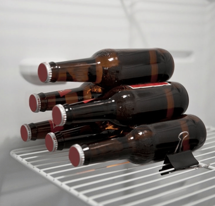 astuce rangement frigo pour des bouteilles en verre, une pince à dessin qui joue le rôle de cale bouteille
