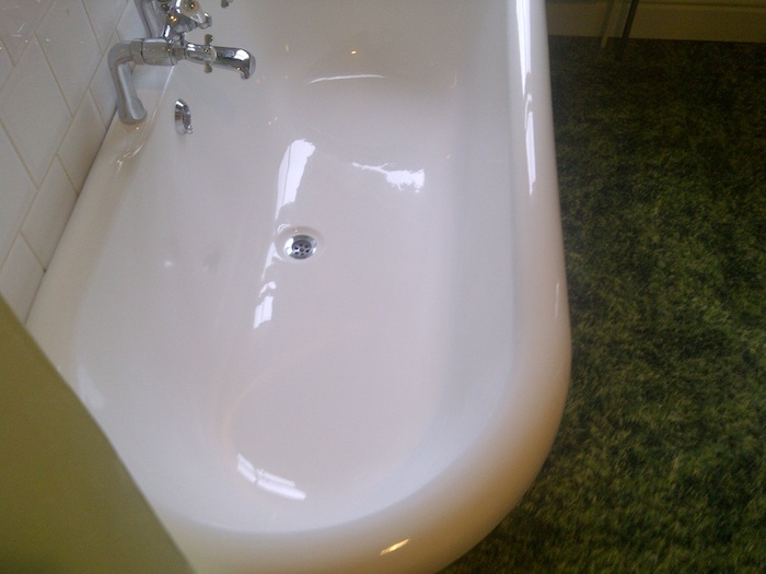 baignoire vintage ovale avec nouvelle peinture blanche brillante epoxy et sol imitation gazon
