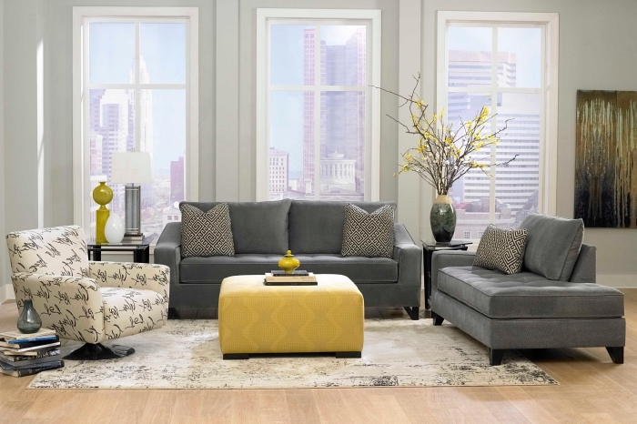 déco de salon gris et jaune avec plancher de bois clair, mobilier salon canapés gris et table ottoman de couleur moutarde