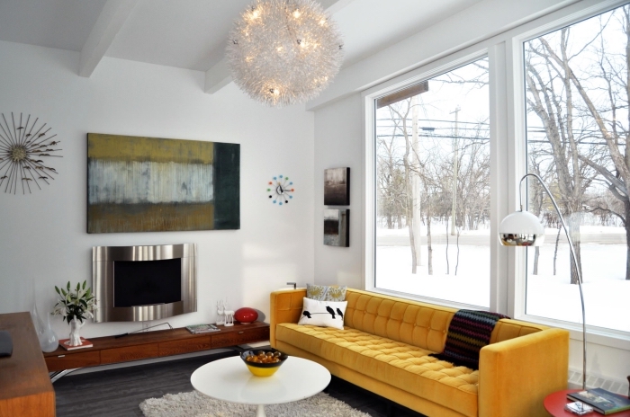 salon cozy aux murs blancs avec poutres plafond apparentes en bois blanc, modèle de canapé moutarde avec coussins
