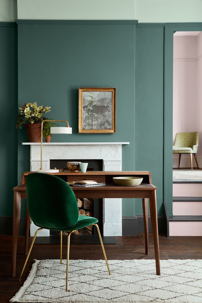 salon aux murs design bicolore de nuances vertes, modèle de bureau bois foncé avec chaise velours vert foncé aux pieds dorés