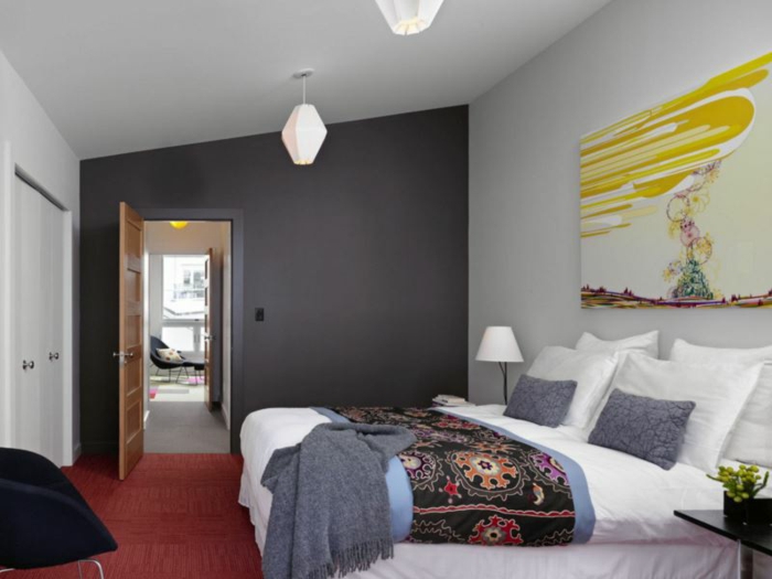 chambre monochrome, tapis rouge, chaise noire, mur gris anthracite, tableau peinture abstraite, plaid ethnique