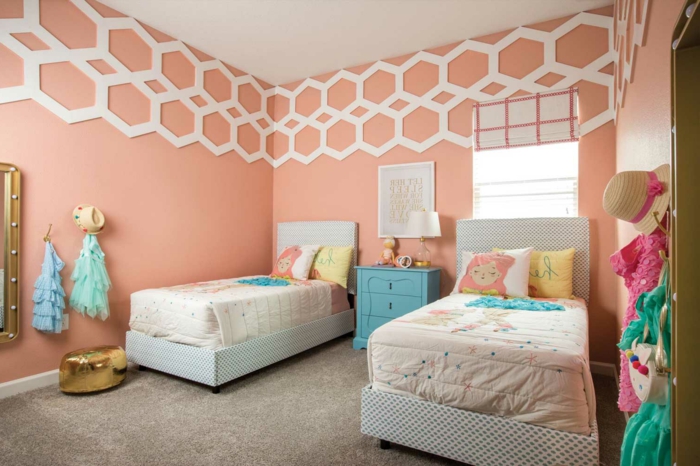 couleur pêche, deux lits, déco en bleu et rose, mur rose, déco géométrique couleur blanche, petit pouf doré
