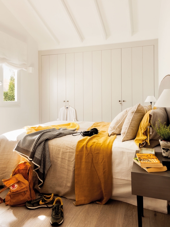 la couleur jaune moutarde en forme accessoires plaid et coussins dans une chambre blanche avec parquet bois clair