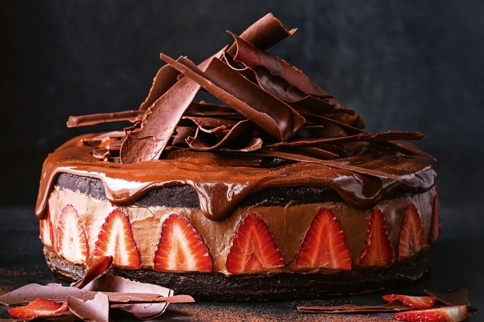idée gateau au nutella super bon, cheesecake au chocolat et fraises sur un fond biscuité décoré de copeaux de chocolat et glaçage coulant