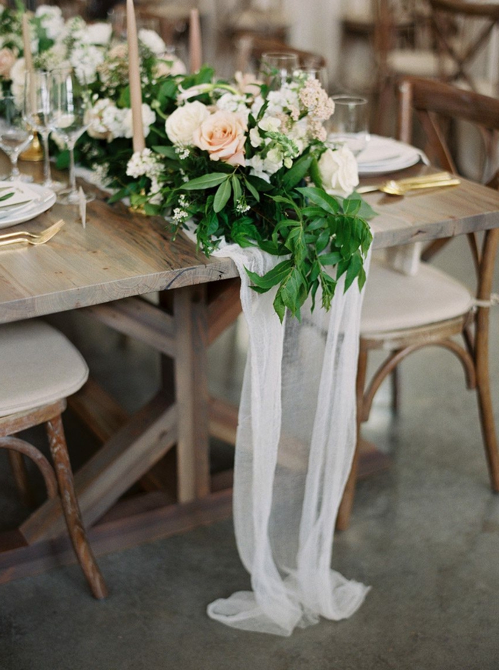 table en bois longue, chaises rétro, mariage rétro chic, guirlande de fleurs et ustensiles dorées