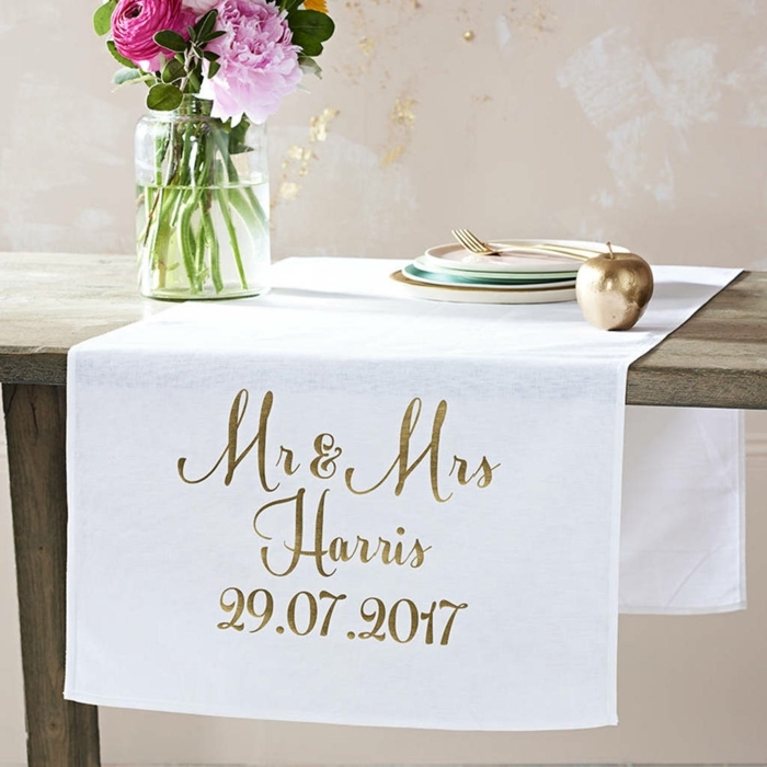 chemin de table blanc avec les initiales des mariés et la date, bocal en verre avec bouquet champêtre