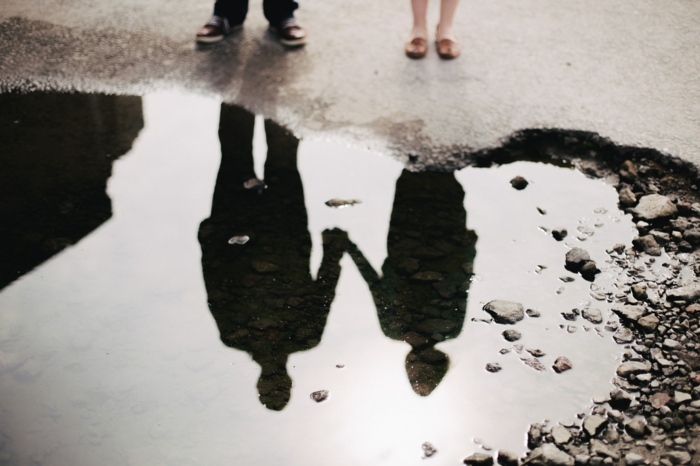 Coeur forme de trou sur le sol, silhouettes de couple amoureux qui se prennent la main, miroir vue sur l'eau 