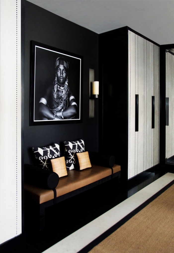 un hall d'entrée noir et blanc aux accents déco ethniques chic avec une belle assise en cuir à côté du placard, decoration couloir d'entrée noir et blanc