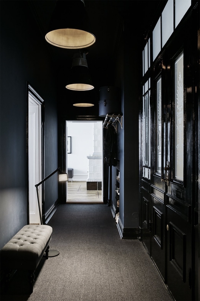 déco couloir étroit de style haussmannien aux murs peint en noir mat qui donne sur un salon blanc